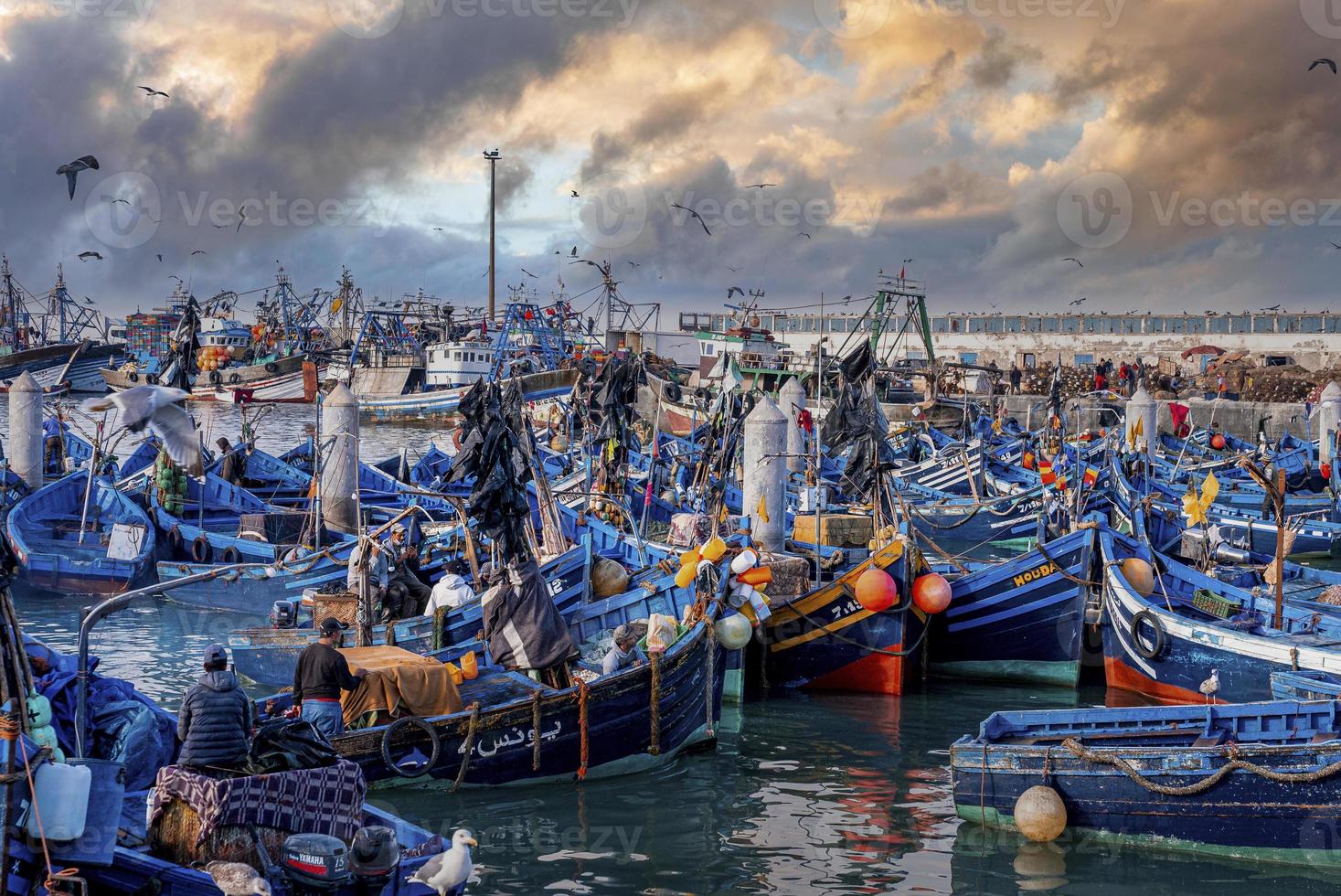 Wooden fishing boats anchored at marina against dramatic cloudy sky photo