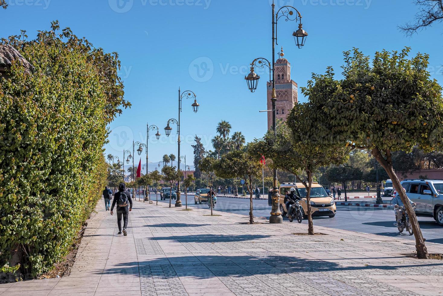 View of pedestrian walking on street with Koutoubia mosque against sky photo