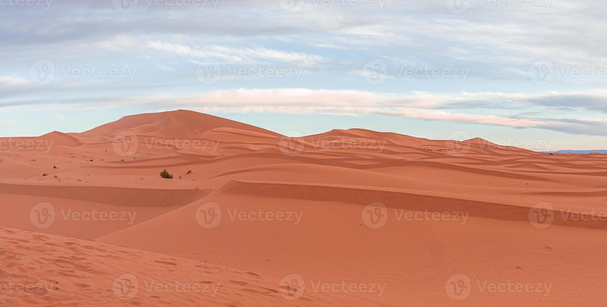 Impresionante vista de las dunas de arena con patrón de ondas en el desierto contra el cielo nublado foto