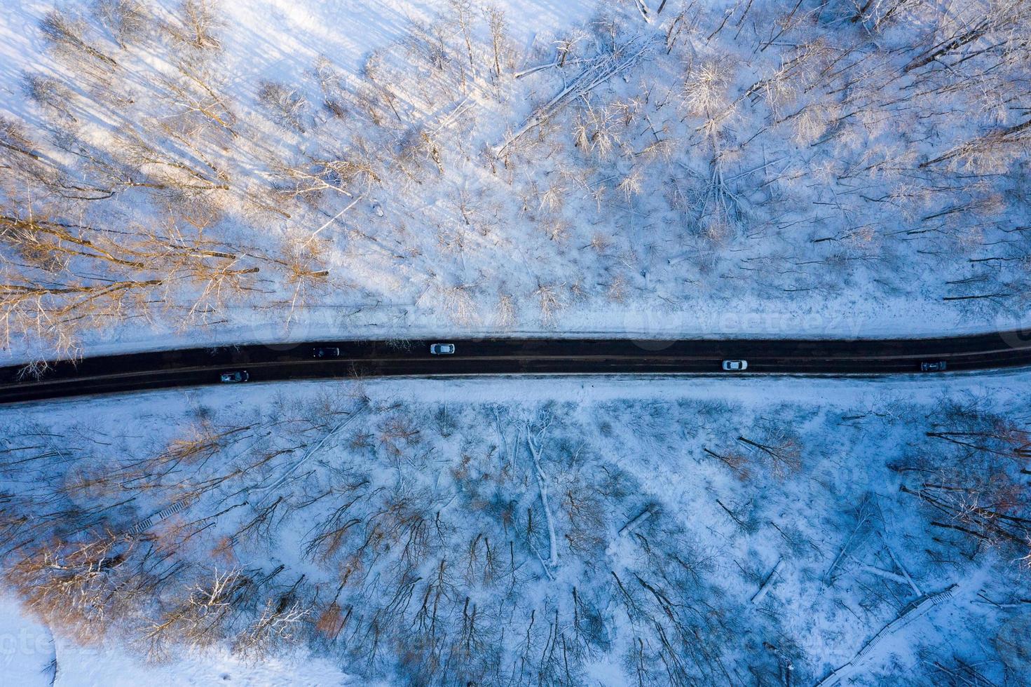 camino ventoso con curvas en el bosque cubierto de nieve, vista aérea de arriba hacia abajo. foto