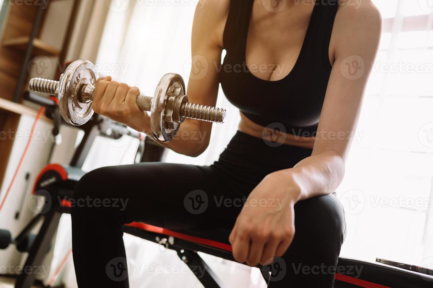 Determined woman losing weight at home and exercising with dumbbells. Sport and recreation concept. photo