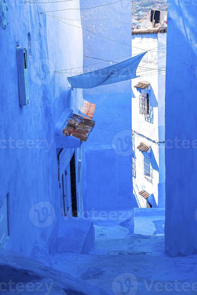 Narrow alley of blue town with staircase leading to residential structures on both side photo