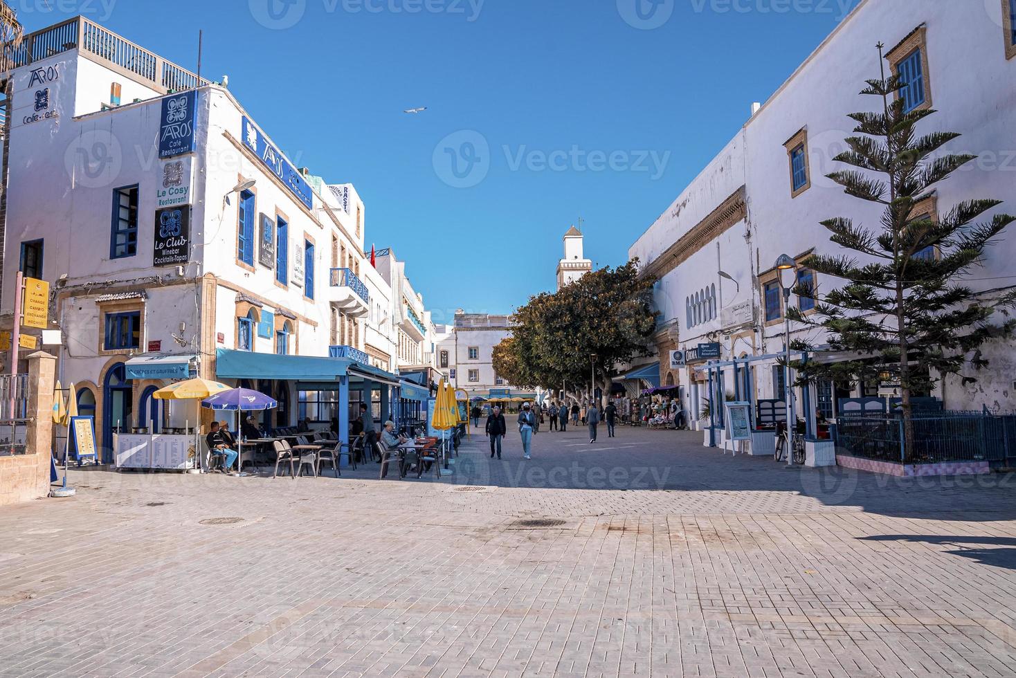 People shopping and walking on busy street with market stalls and shops photo