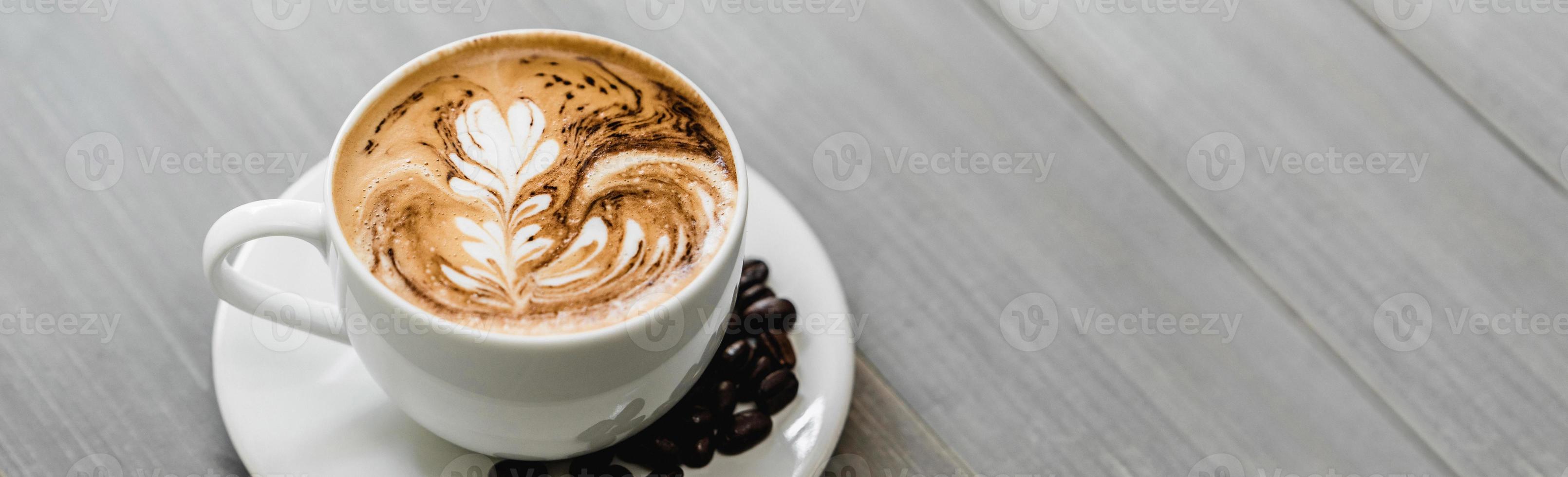 Fresh brewed coffee with fern pattern latte art in white cup photo