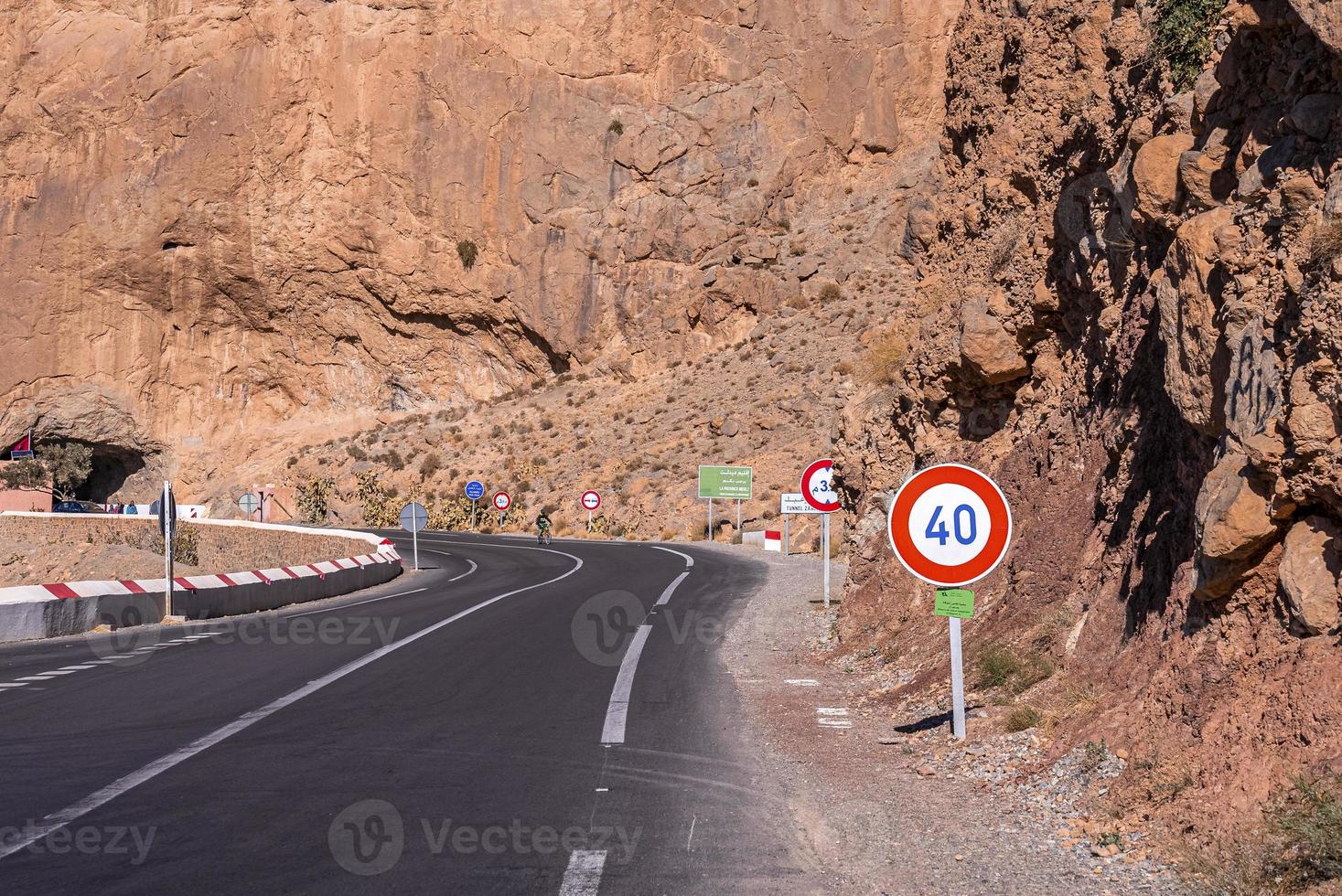 carretera asfaltada con marcas y señales de límite de velocidad a través de la montaña foto