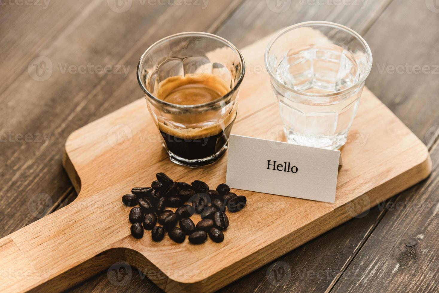 Fresh brewed black Espresso coffee and water in shot glasses served on wooden platter ready to drink photo