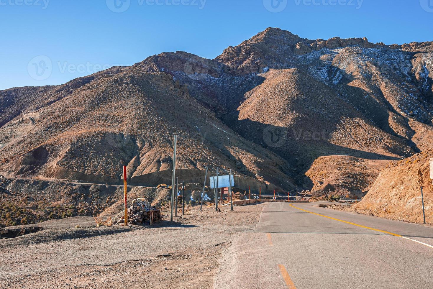 Empty asphalt curvy road through mountains in sunny summer day photo