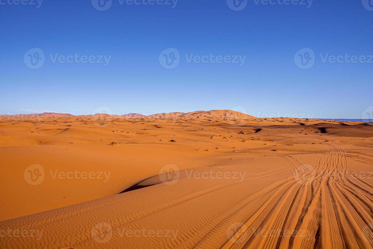 impresionantes vistas de las dunas de arena con marcas de neumáticos en el desierto contra el cielo despejado foto