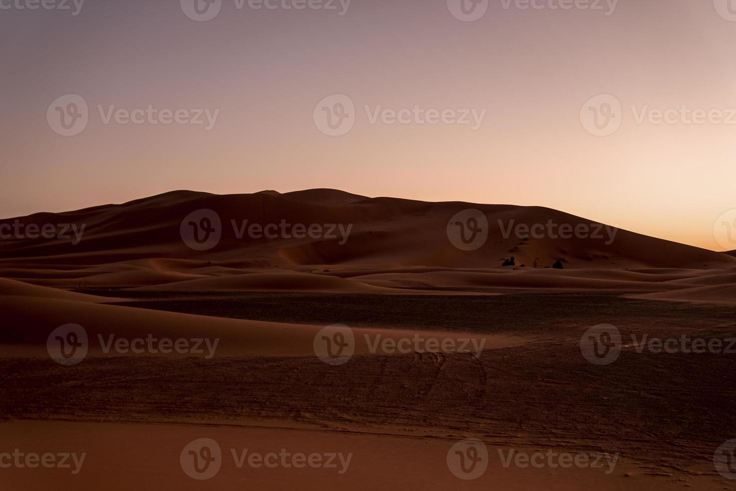 Amazing view of sand dunes in desert against clear sky during sunset photo