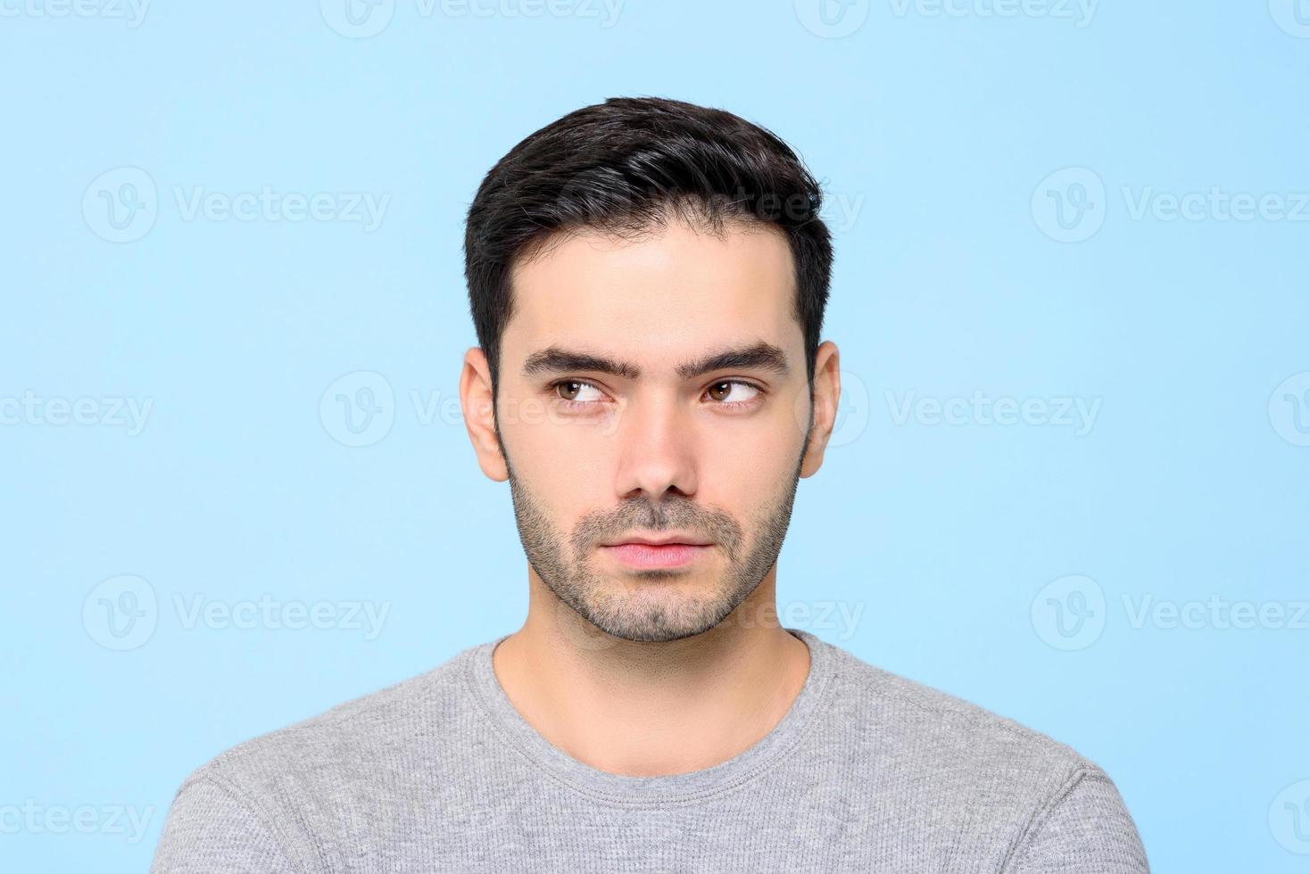 Close up portrait of handsome man thinking with eyes looking sideways isolated on blue studio background photo