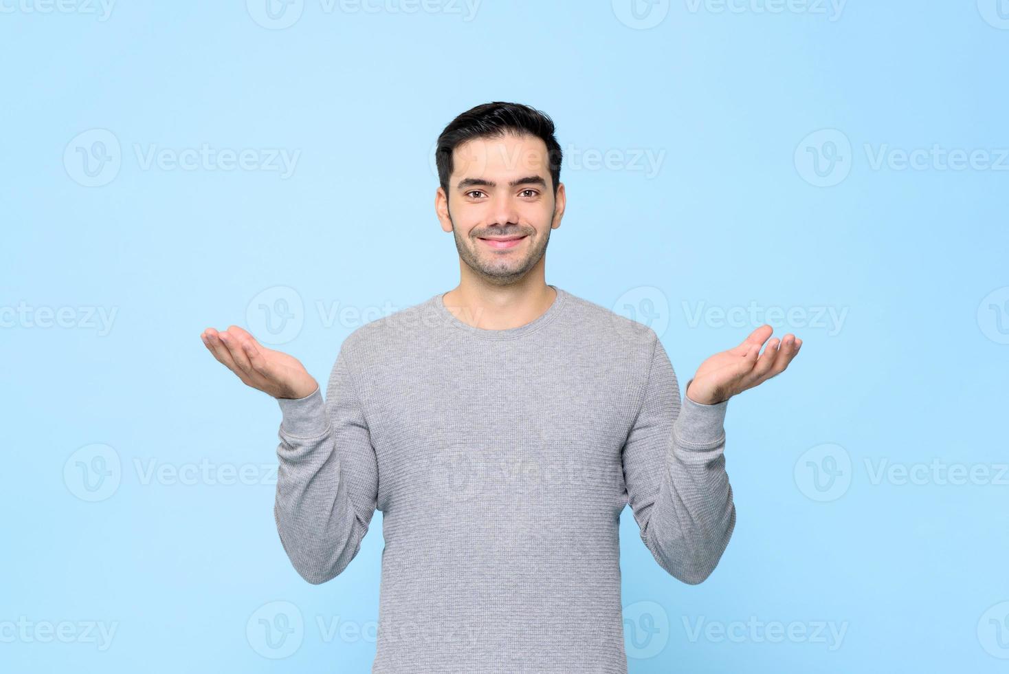 Half body portrait of smiling man in gray t-shirt with open hand gesture in light blue studio background photo