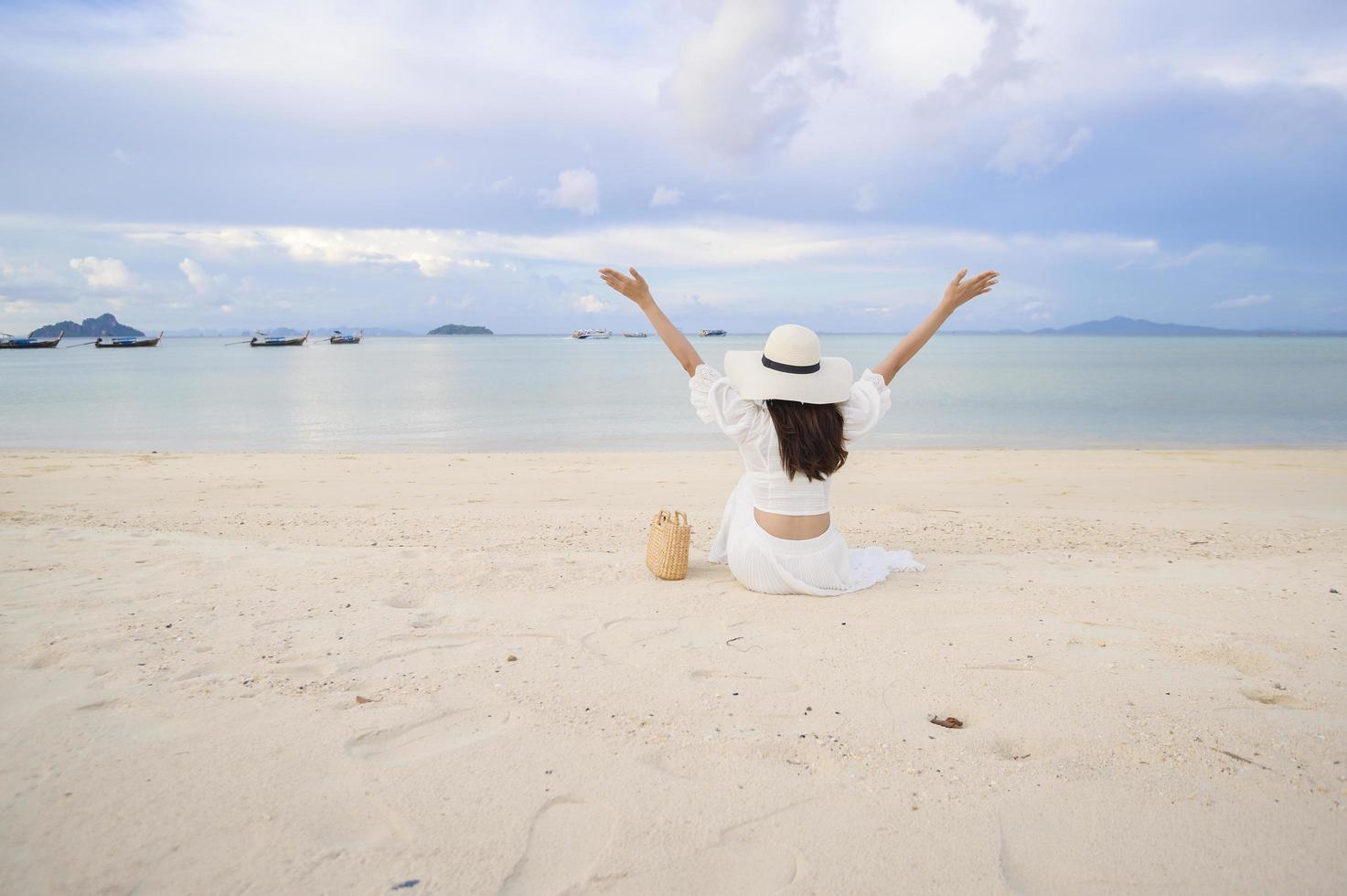 una hermosa mujer feliz con vestido blanco disfrutando y relajándose en el concepto de playa, verano y vacaciones foto