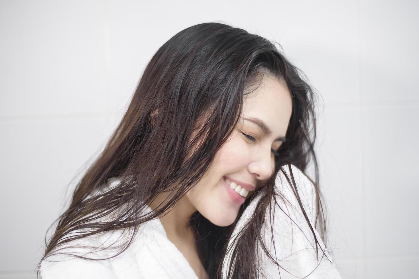 A woman is drying her hair with a towel after showering photo