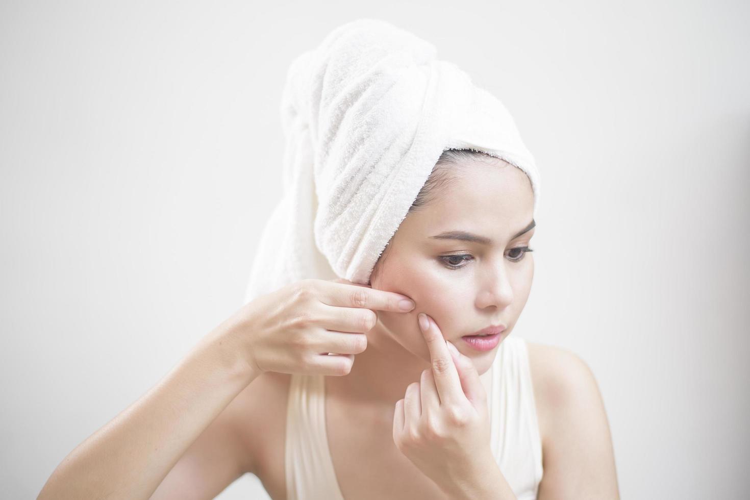 A woman is popping a pimple photo