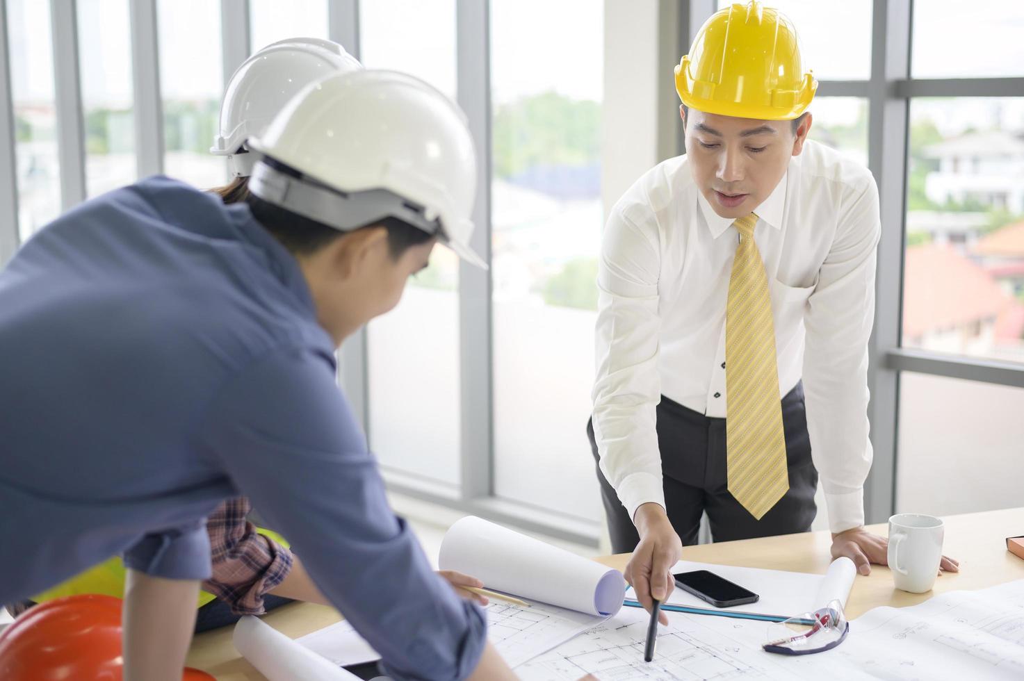 los ingenieros son planes de construcción analíticos con planos en la oficina foto