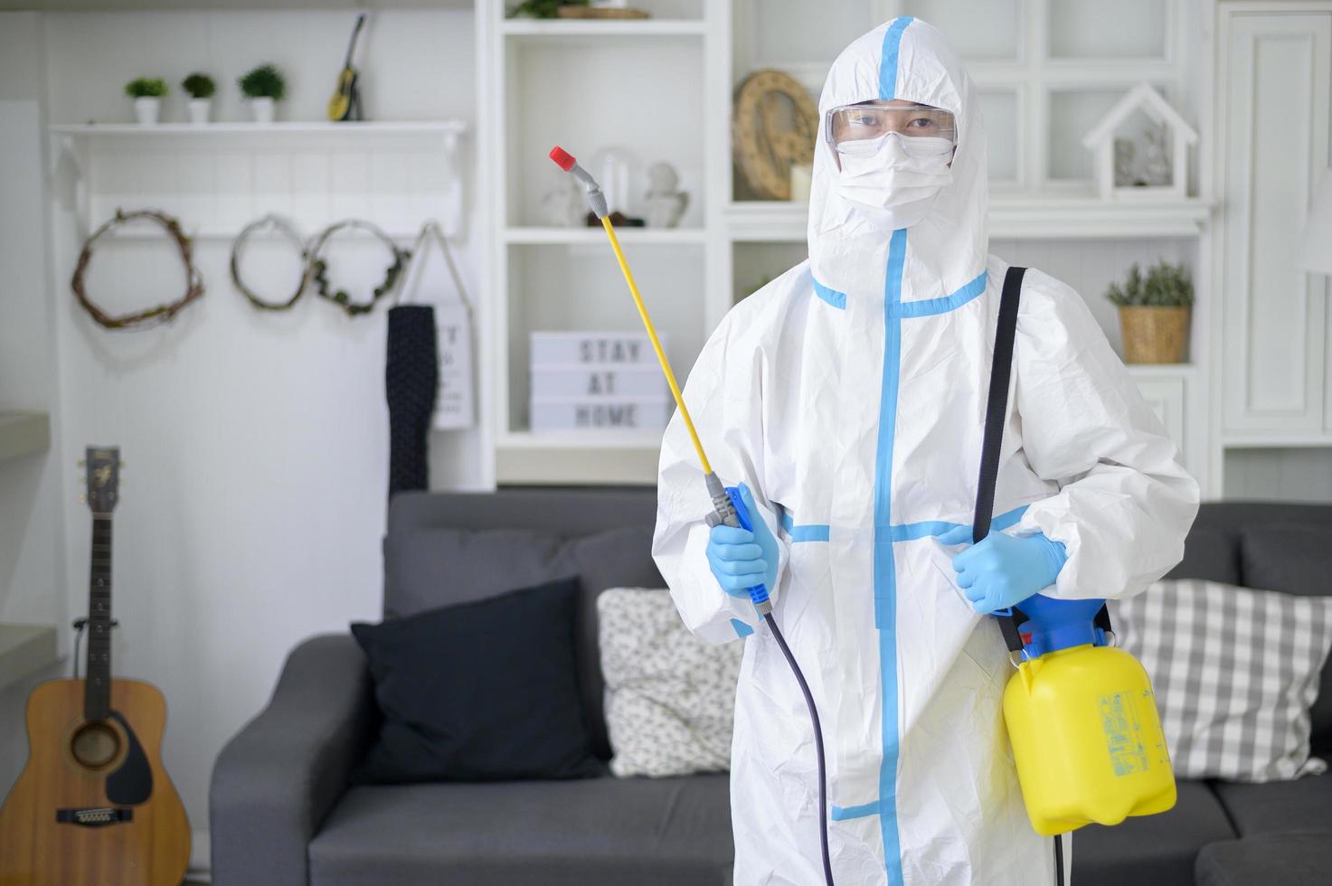 un personal médico con traje de ppe está usando spray desinfectante en la sala de estar, protección covid-19, concepto de desinfección. foto