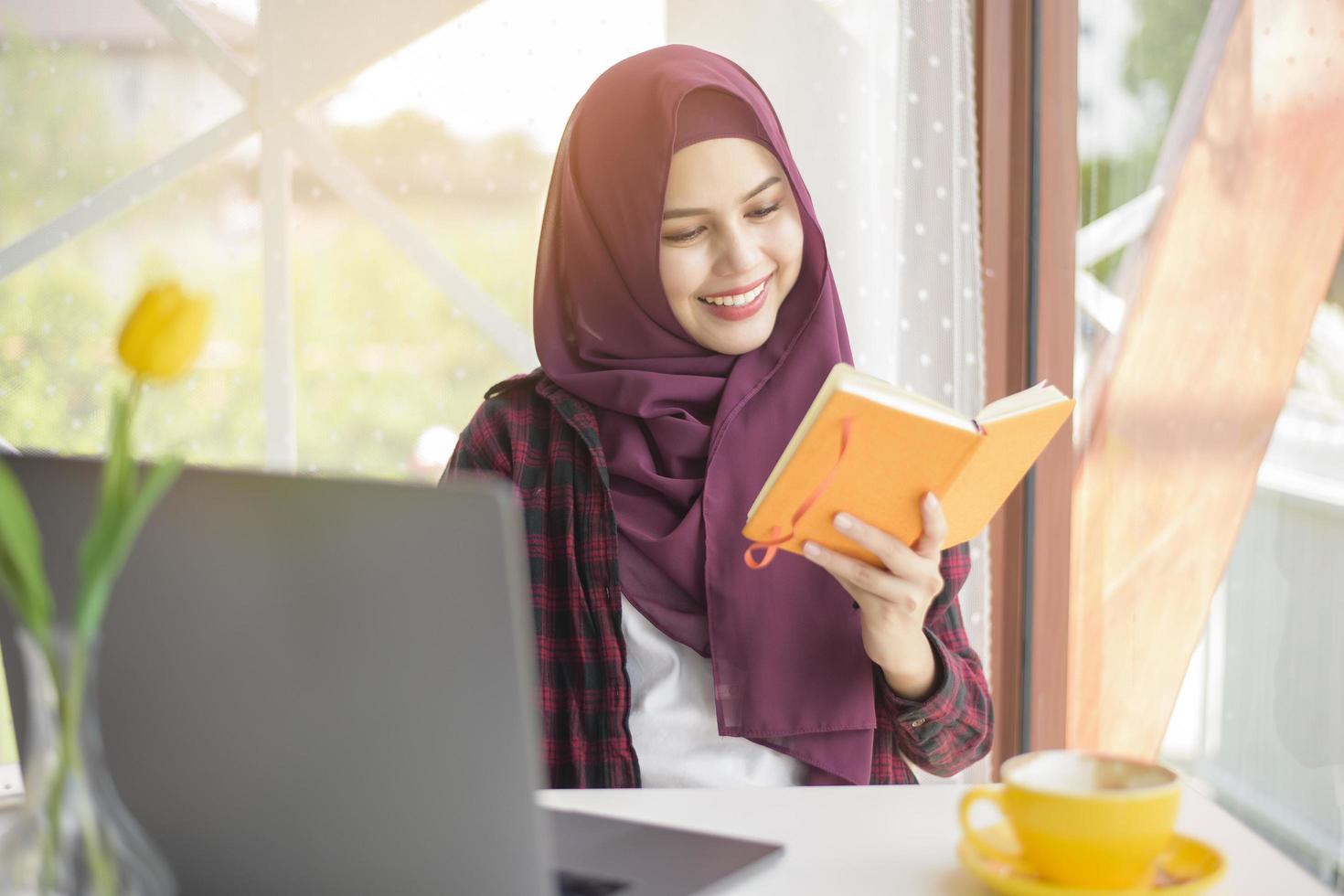 mujer musulmana con hiyab está trabajando con una computadora portátil en una cafetería foto