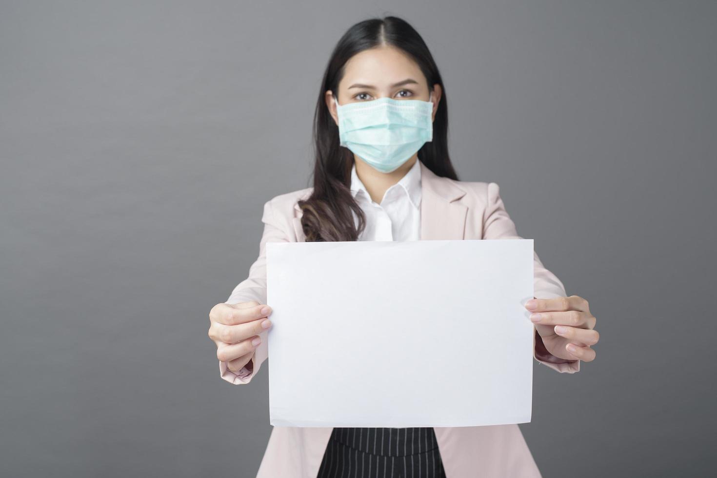 Business woman with  surgical mask is holding blank paper photo