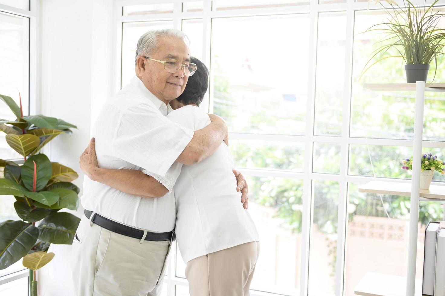 A senior elderly couple are hugging in home photo