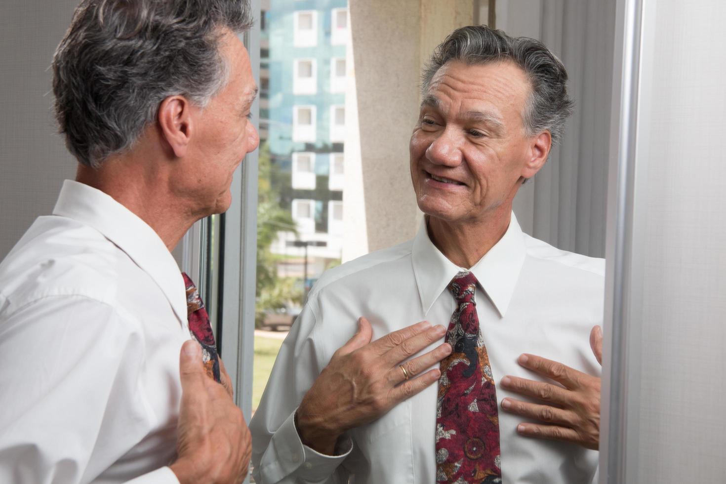 Mature Business Man Tying his Neck Tie in Front of a Mirror photo