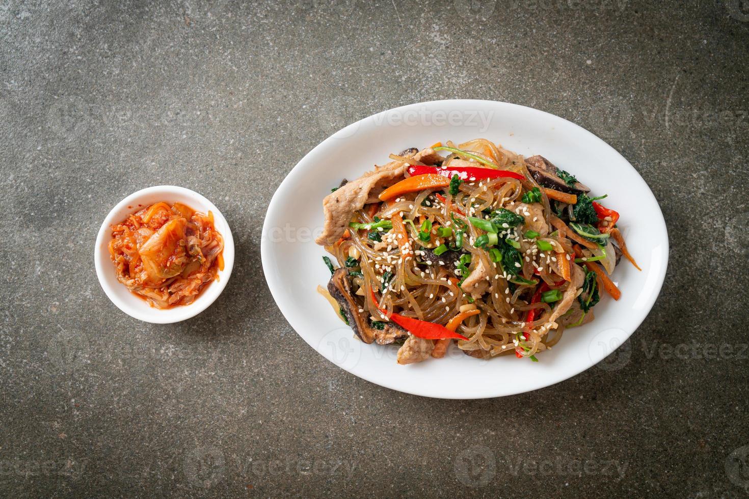 japchae or stir-fried Korean vermicelli noodles with vegetables and pork topped with white sesame photo