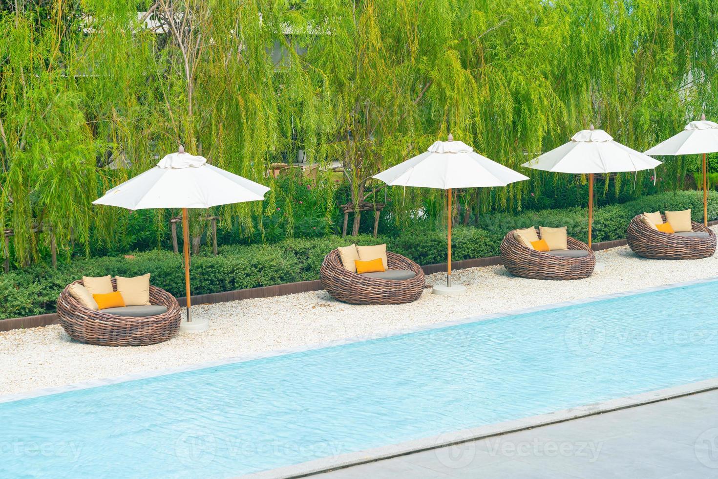 outdoor patio chair with pillow and umbrella around swimming pool photo