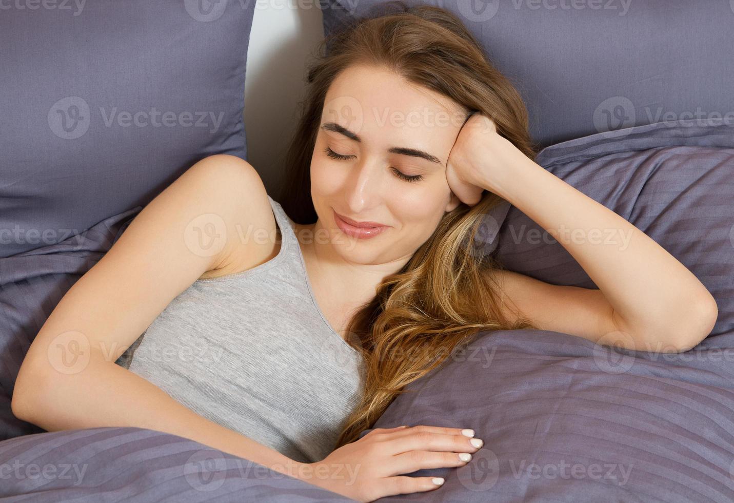 Cierra a una chica feliz despertándose en la cama por la mañana. foto