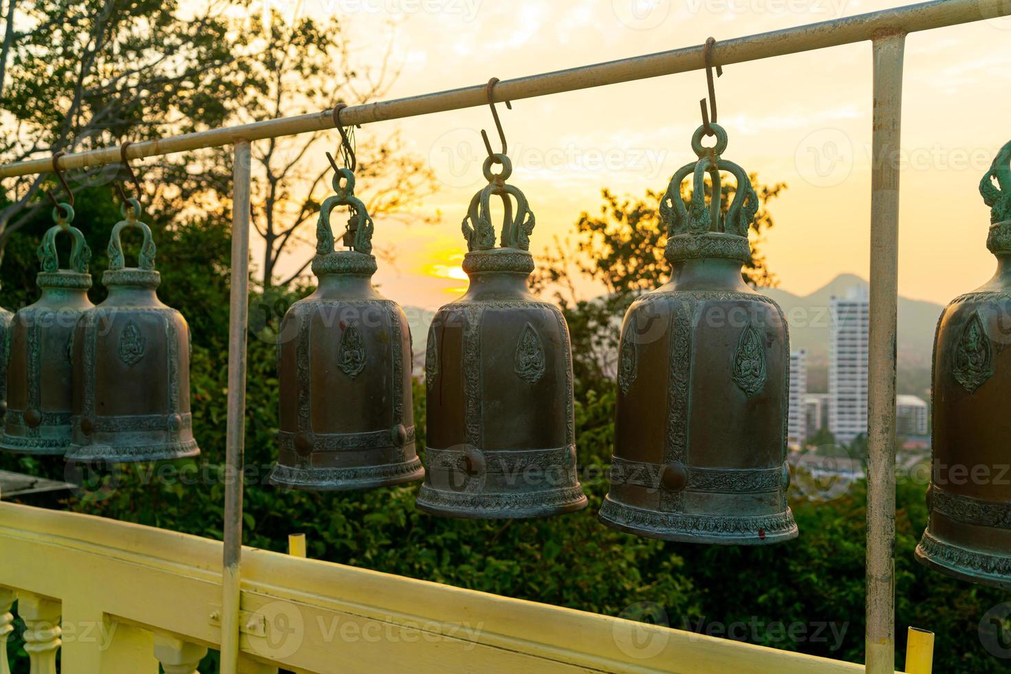 metallic bells hanging in a row outside in thai buddhist temple photo