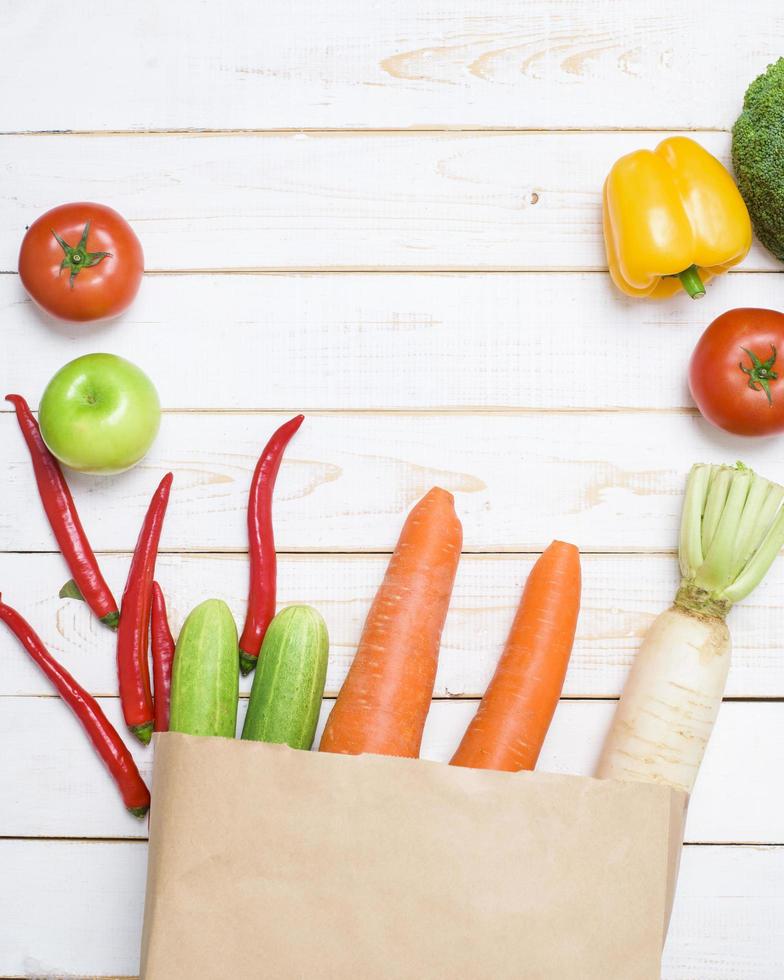 vegetables in grocery bag on white wood background photo