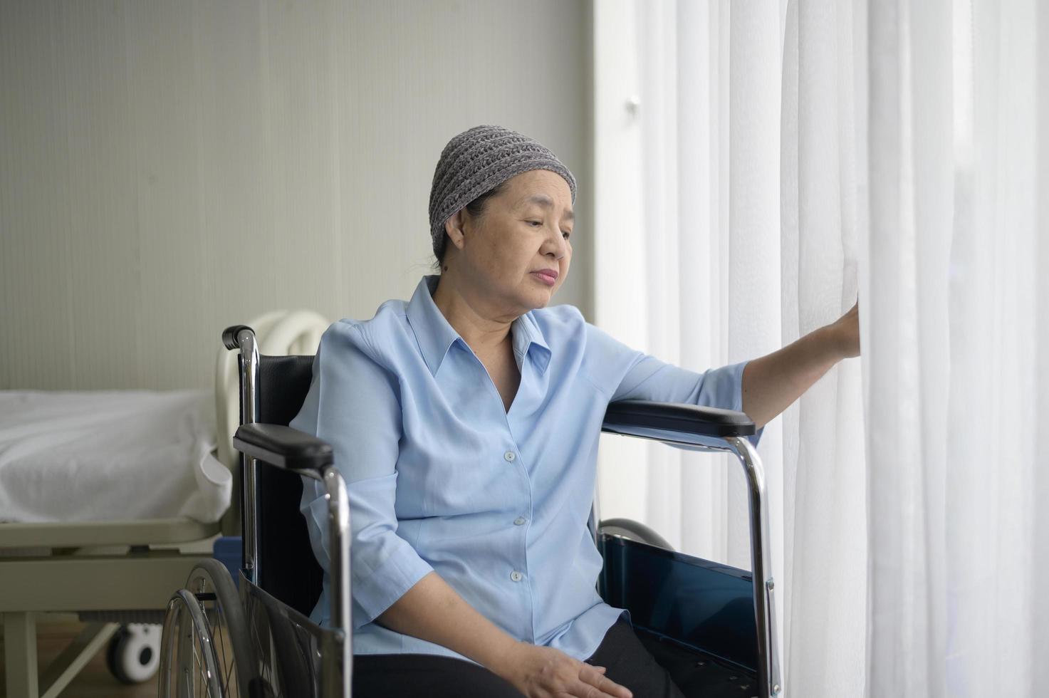 Depressed and hopeless Asian cancer patient woman wearing head scarf in hospital. photo