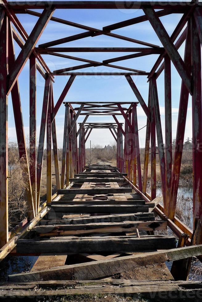 Open metal tunnel on the bridge. Cuckoo railway over the swamp. photo