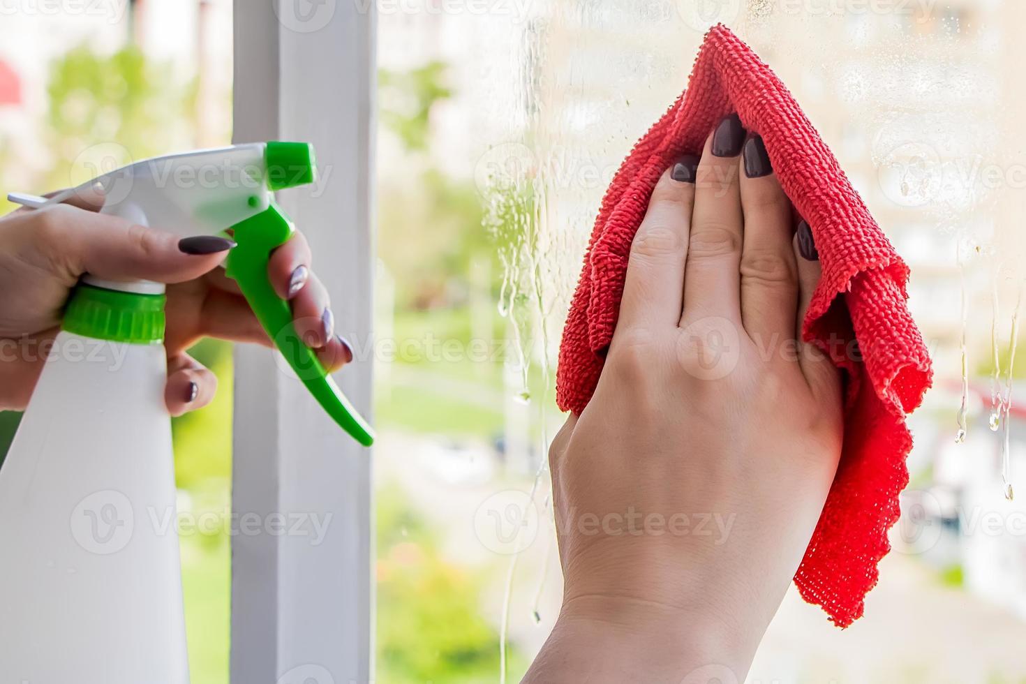 Woman sprays a detergent on a glass. photo