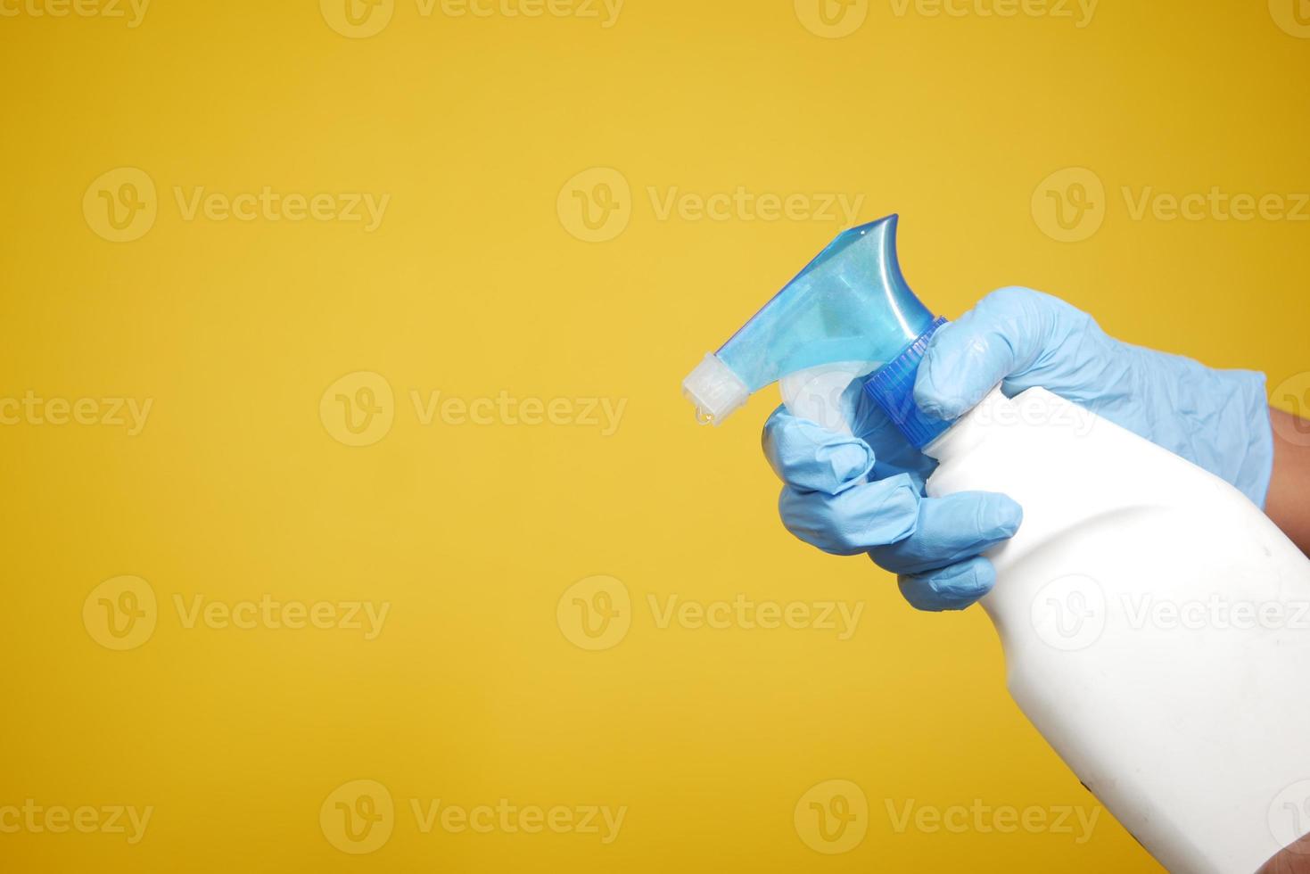 hand in blue rubber gloves holding spray bottle with copy space photo