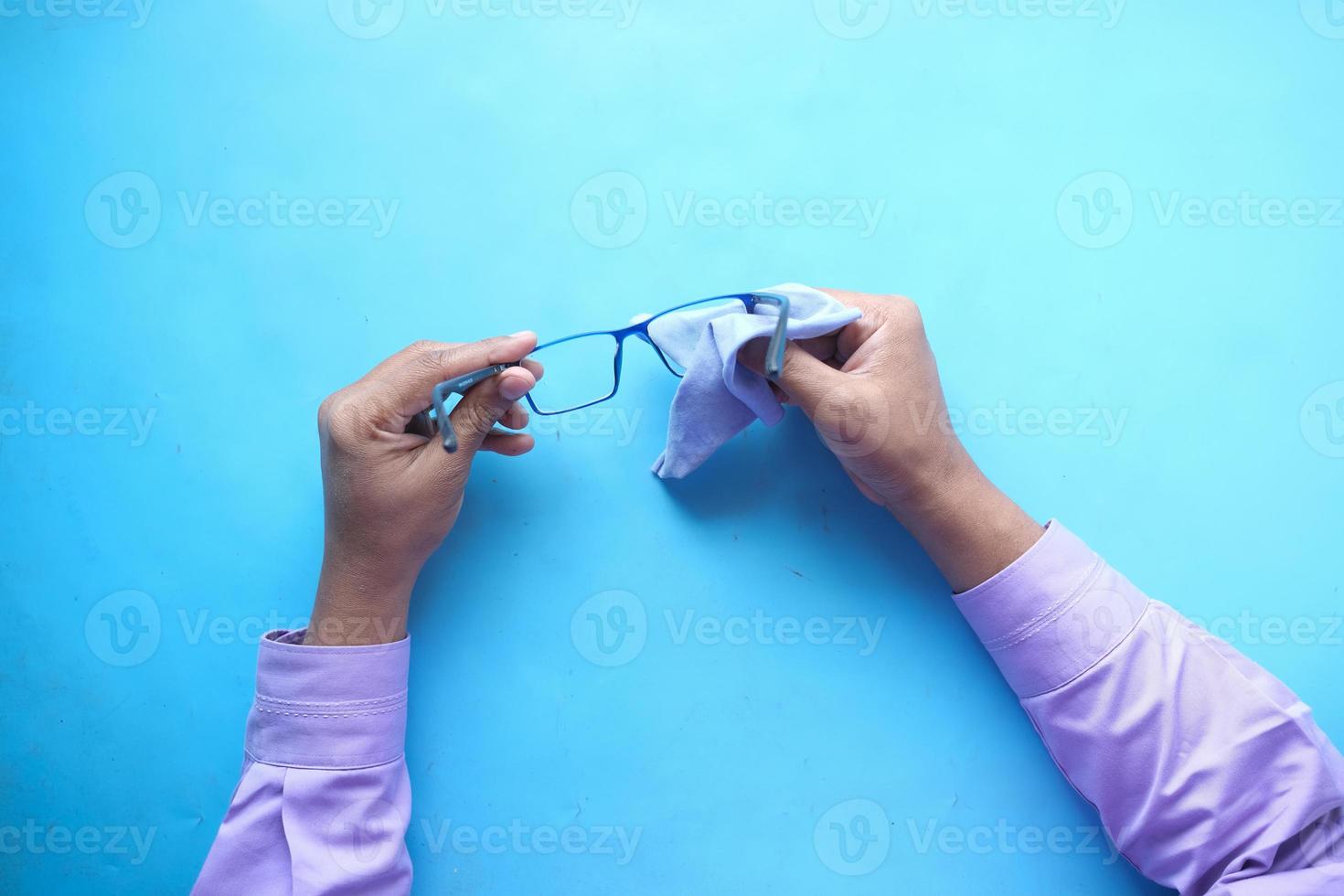 cleaning eyeglass with tissue close up photo