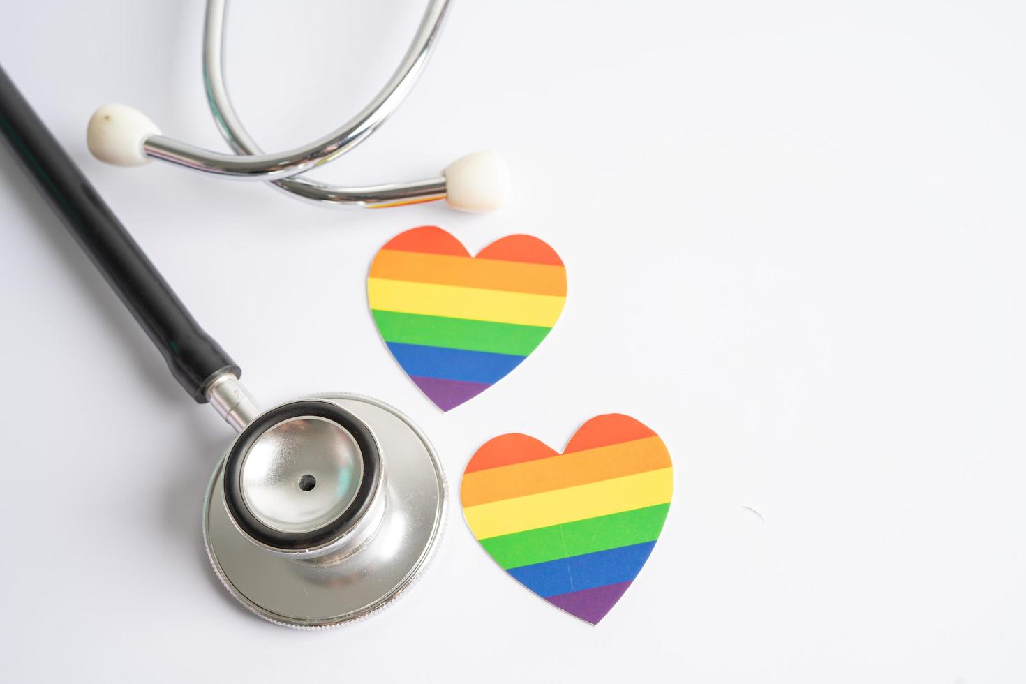 estetoscopio negro con el corazón de la bandera del arco iris sobre fondo blanco, símbolo del mes del orgullo lgbt, celebración anual social en junio, símbolo de gay, lesbiana, bisexual, transgénero, derechos humanos y paz. foto