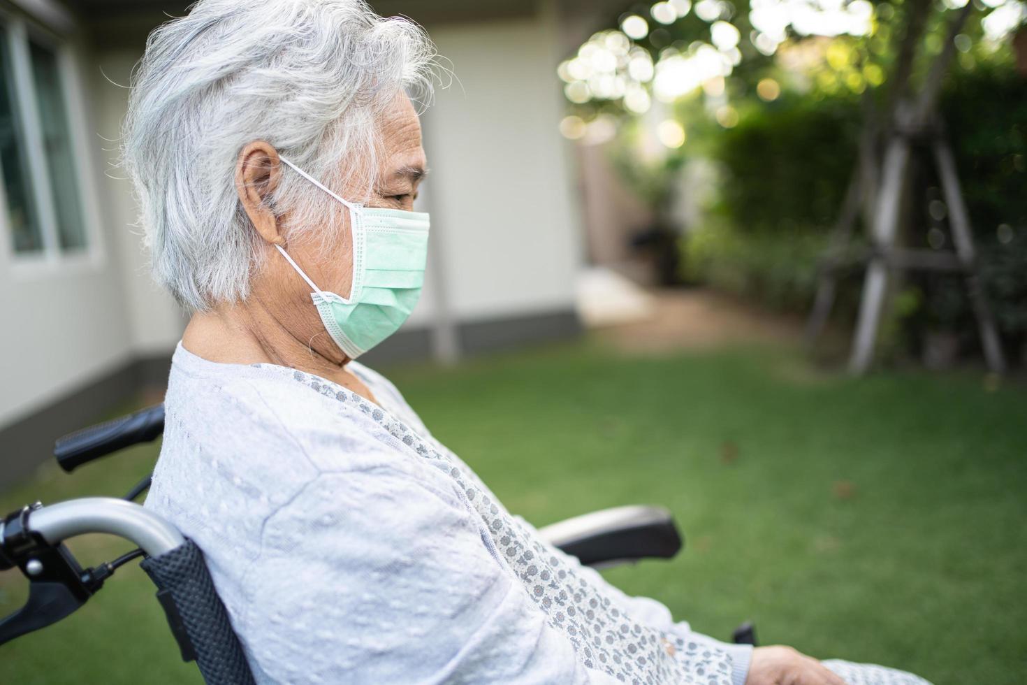 anciana asiática o anciana en silla de ruedas y con una máscara facial para proteger la infección de seguridad covid-19 coronavirus en el parque. foto