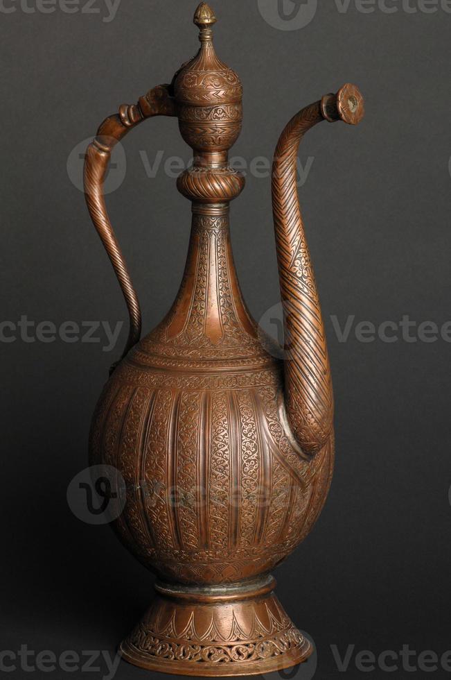 ancient oriental metal teapot on dark background. antique bronze tableware photo