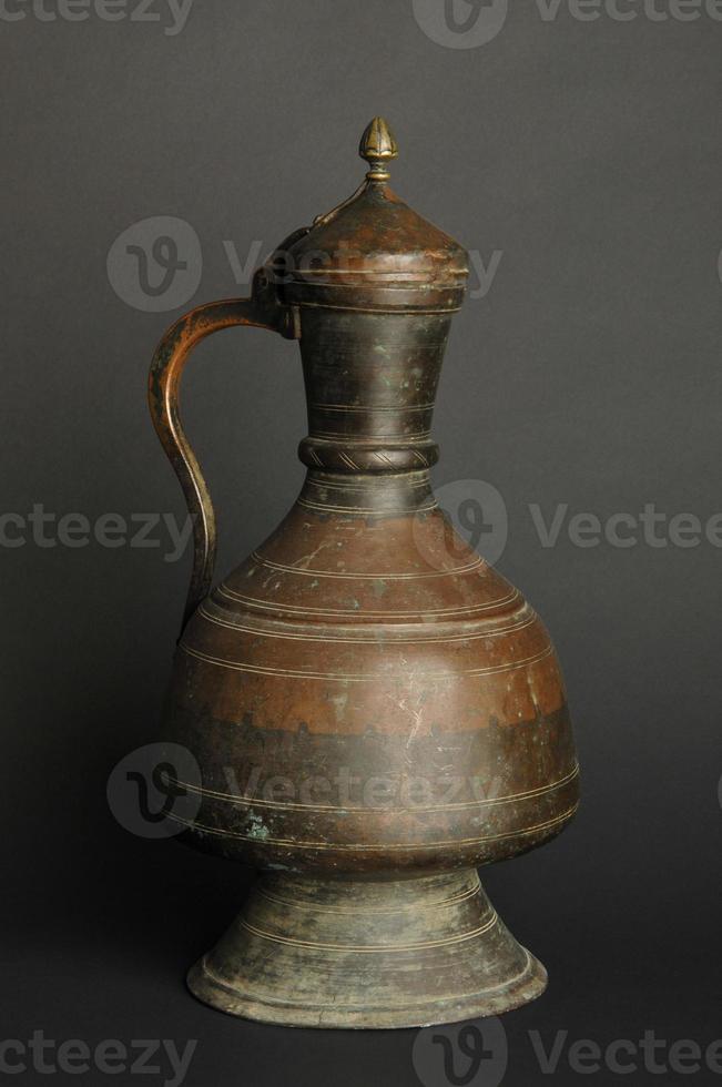 antigua jarra de metal oriental sobre fondo oscuro. vajilla antigua de bronce foto