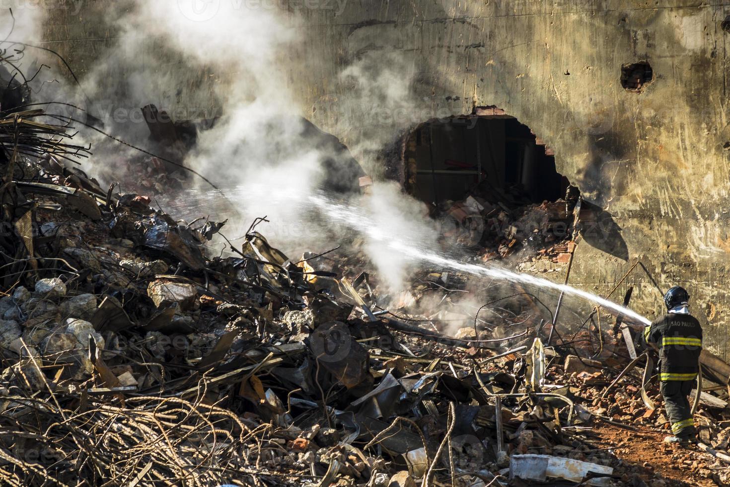 Brazilian firefighter fights flames in the rubble where a 24-story building collapsed after a fire in downtown Sao Paulo, photo