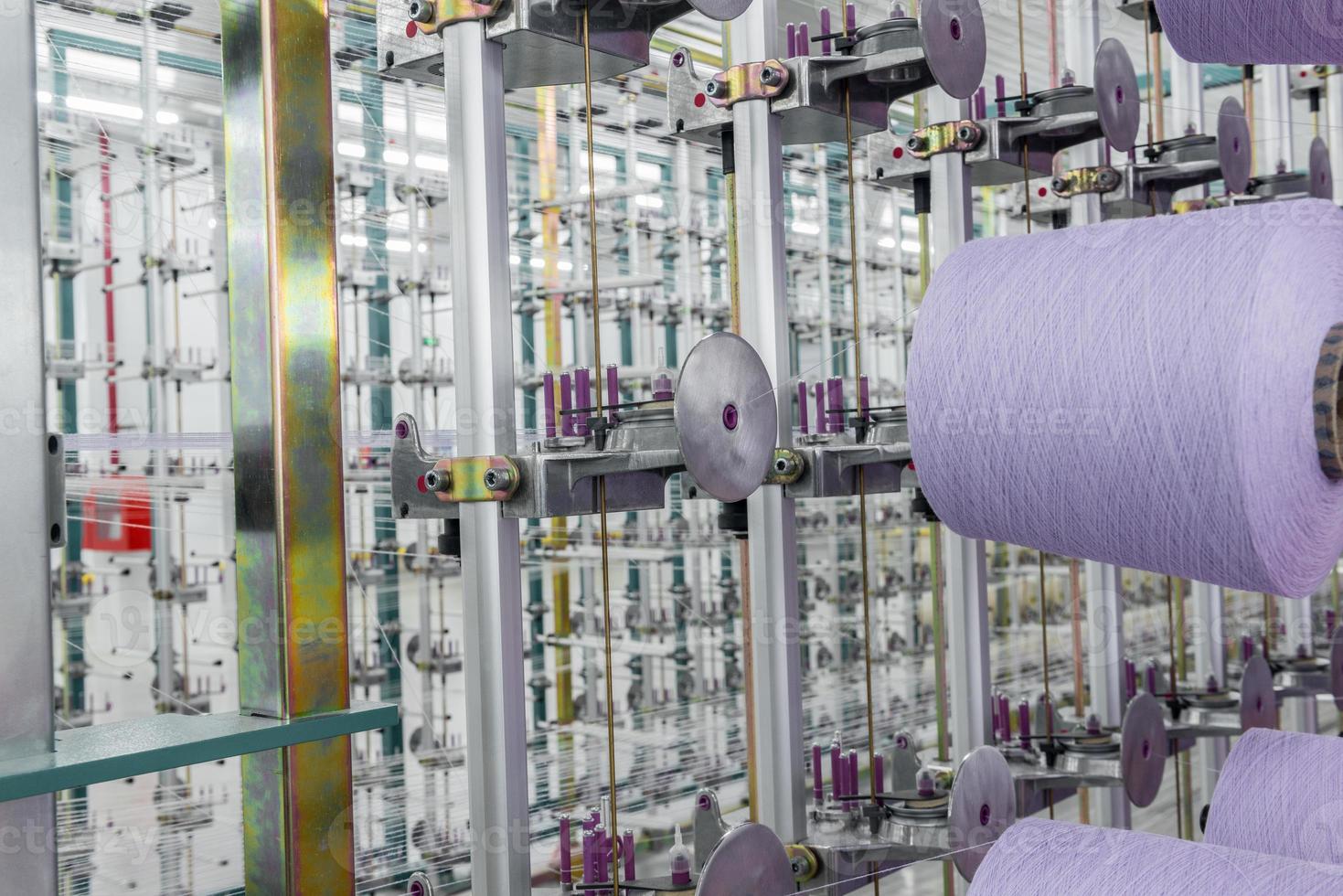 hilo textil púrpura en la máquina de deformación. maquinaria y equipo en una fabrica textil foto