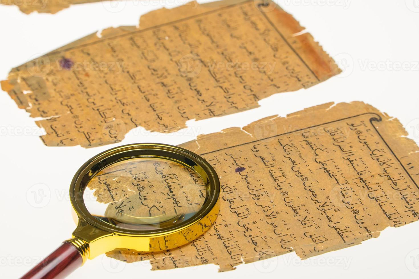 páginas de libros con un manuscrito árabe sobre una mesa con luz y lupa. paleografía, el estudio de la escritura árabe antigua foto