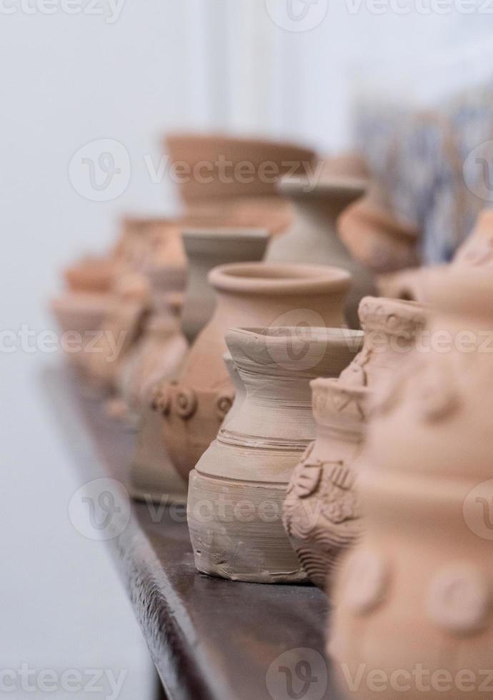 row of clay pots on the shelf, blurred background. children's crafts photo