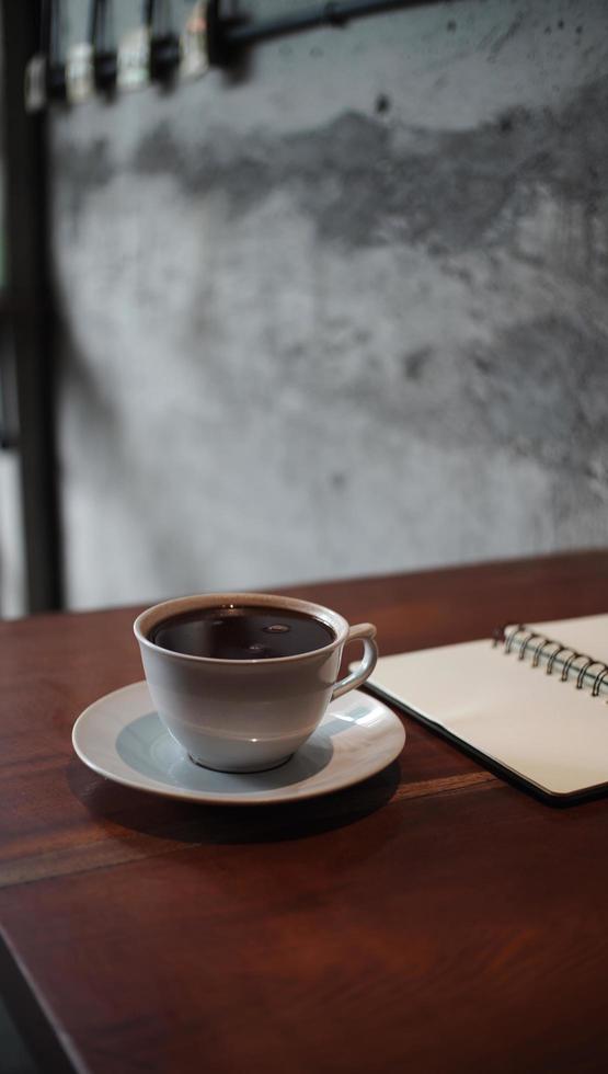 cuaderno abierto y una taza de café en el escritorio de madera foto