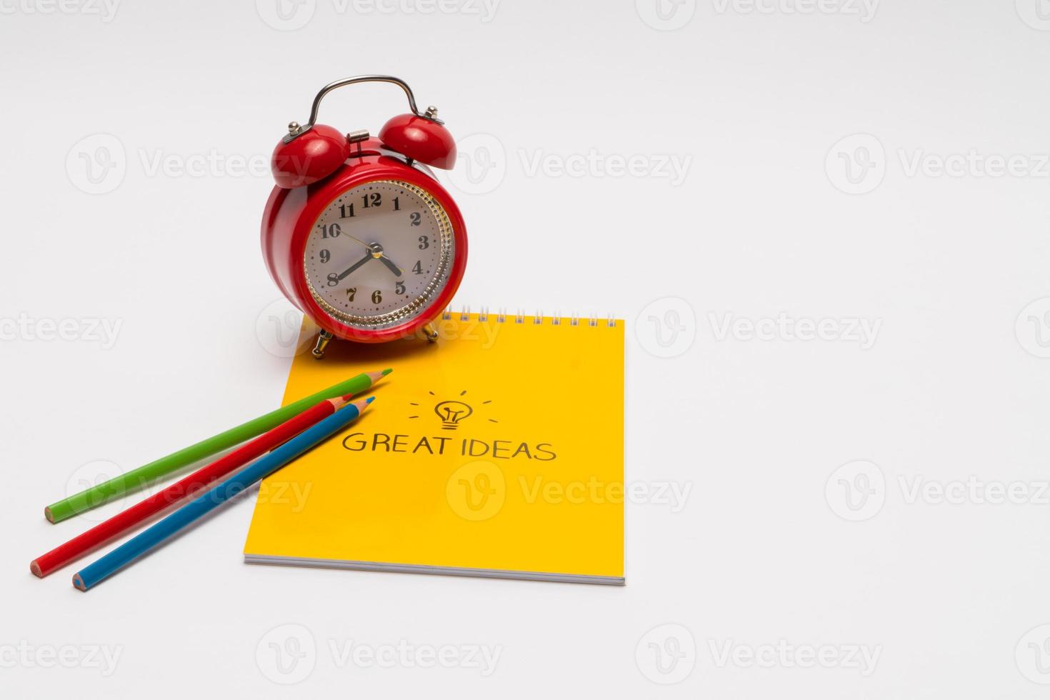 alarm clock with notepad and colored pencils on white background, isolated. back to school. great ideas photo