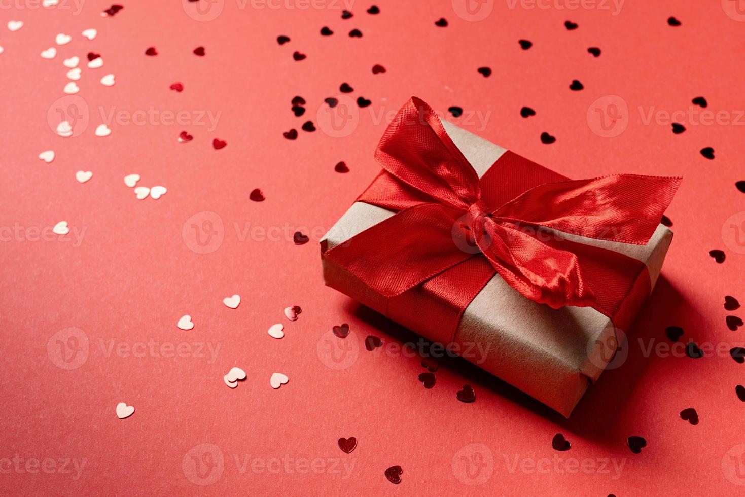 Red gift box with a ribbon for Valentines Day celebrating on red solid background with copy space photo