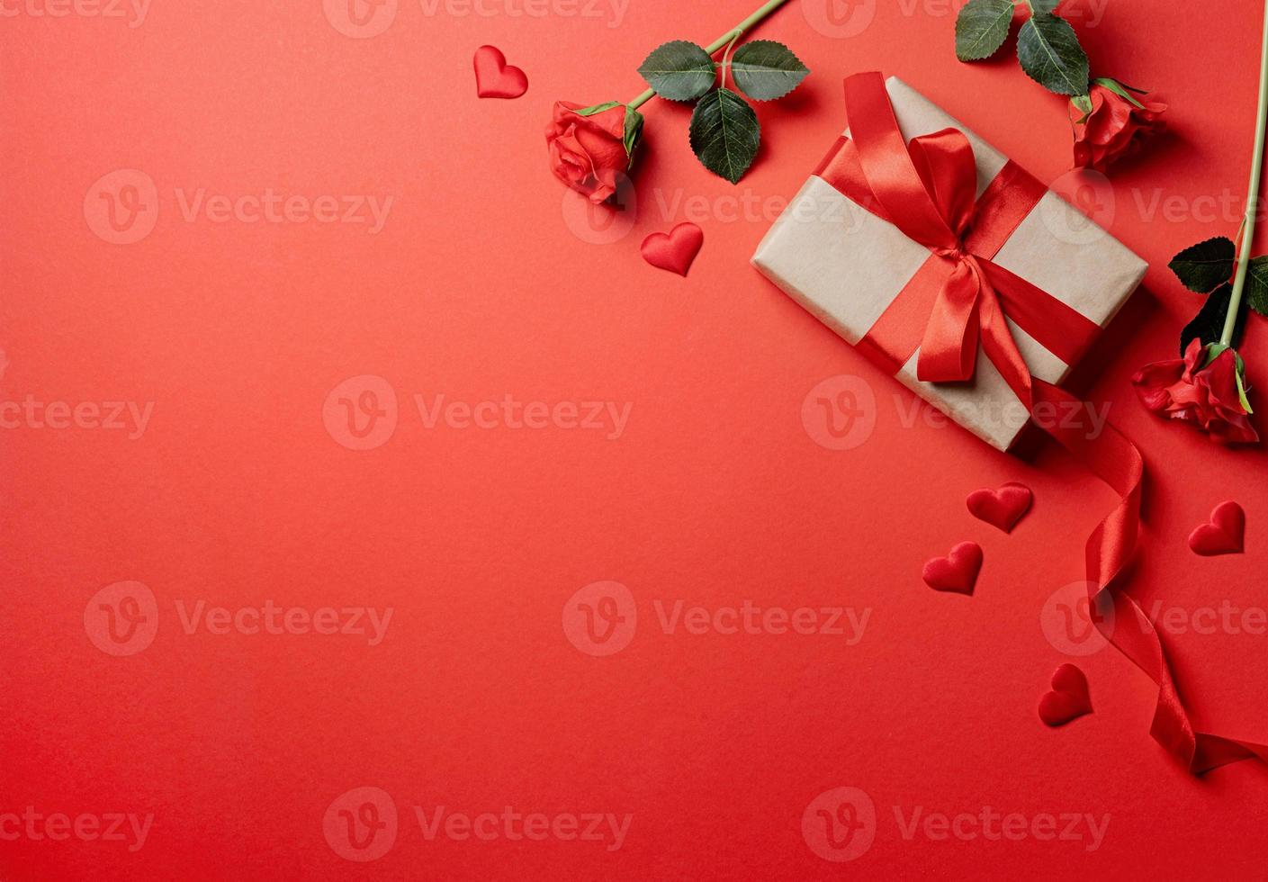 Valentines Day gifts, roses and confetti on red backdrop, copy space photo