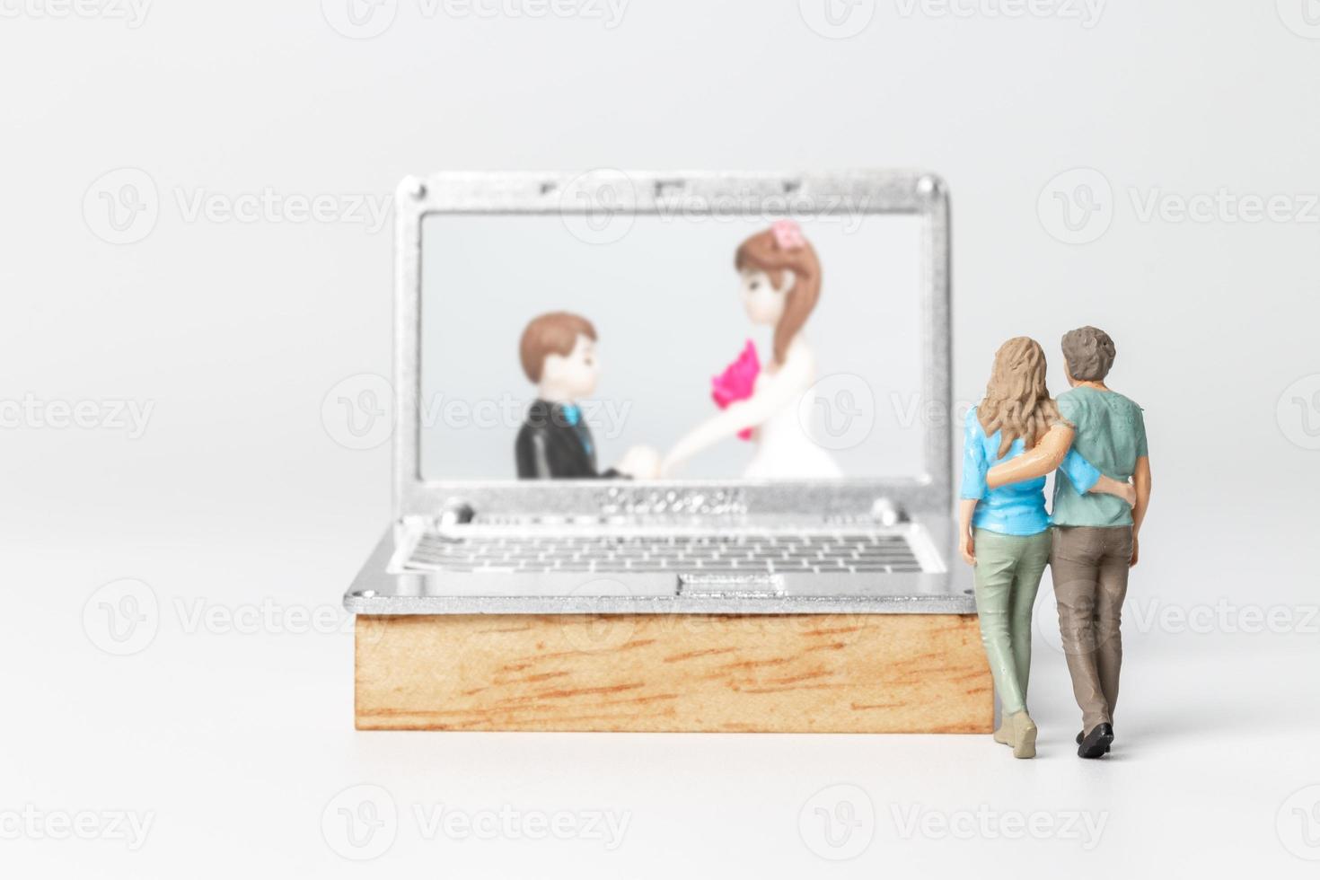 Miniature people Bride and groom virtual wedding on computer screen photo