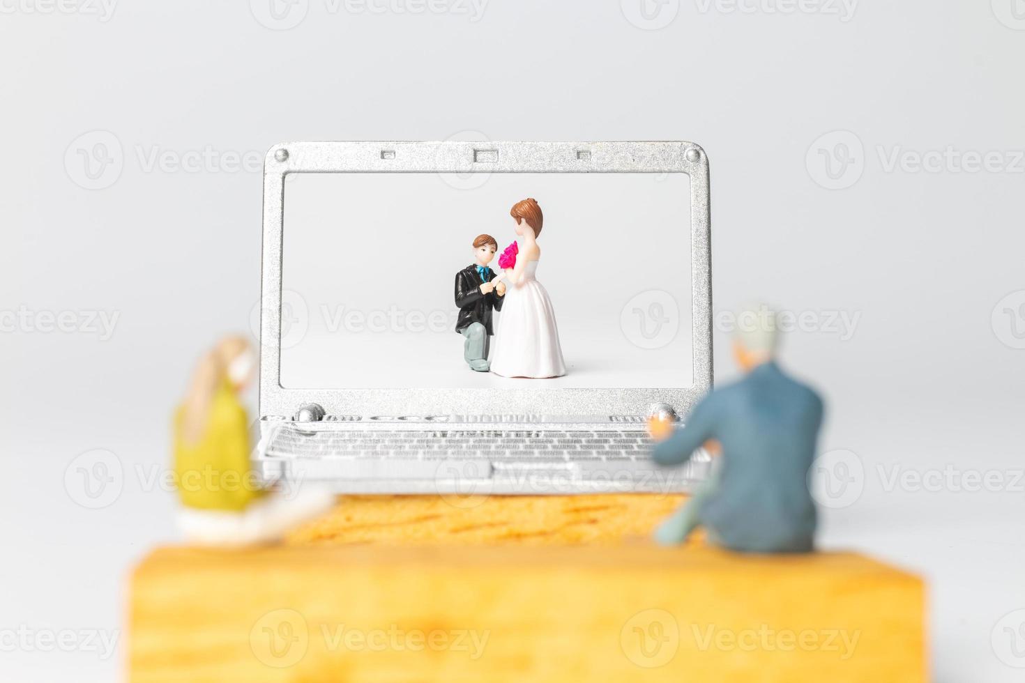 Miniature people Bride and groom virtual wedding on computer screen photo