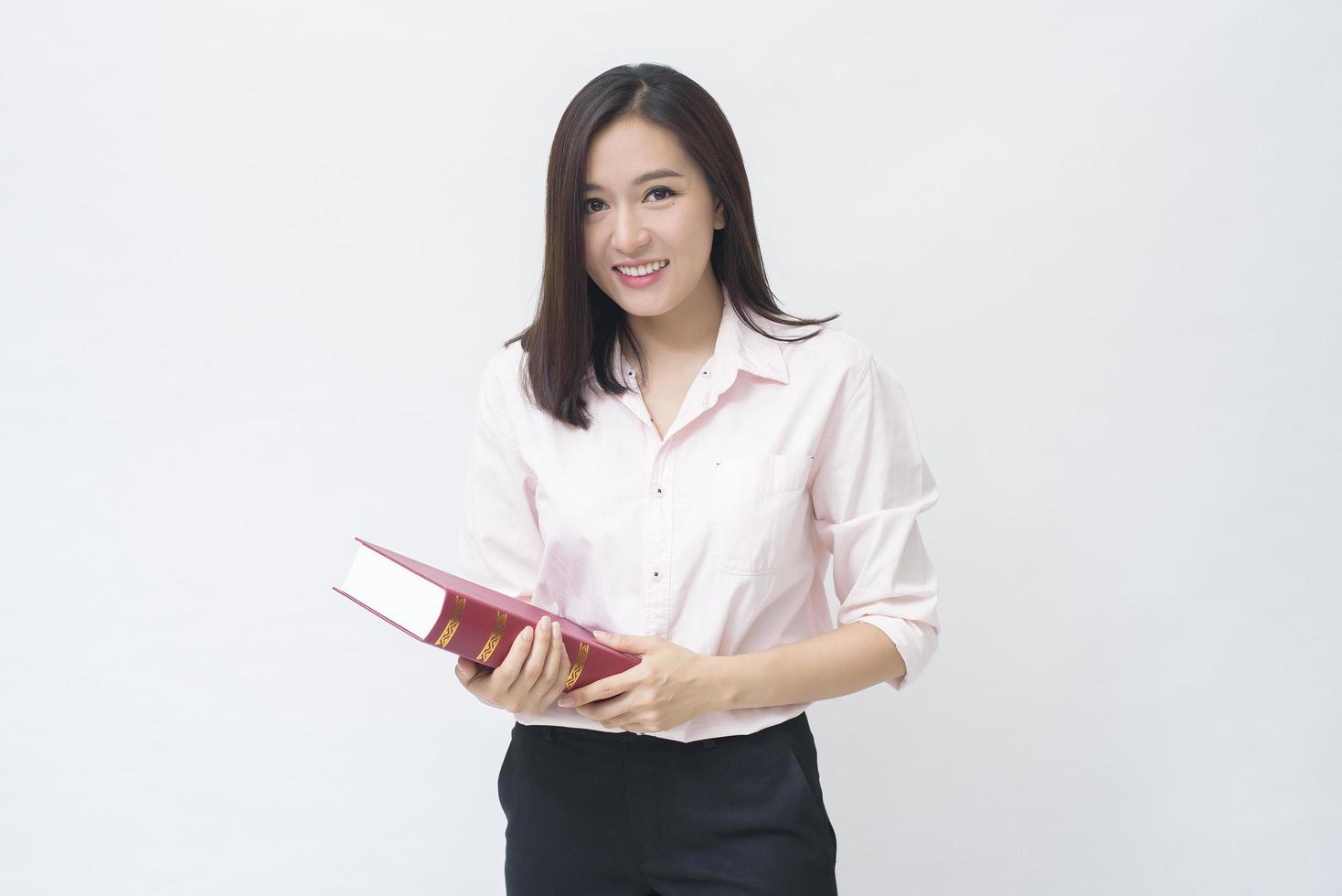 retrato de una hermosa estudiante con camisa rosa sosteniendo un libro aislado sobre un estudio de fondo blanco foto