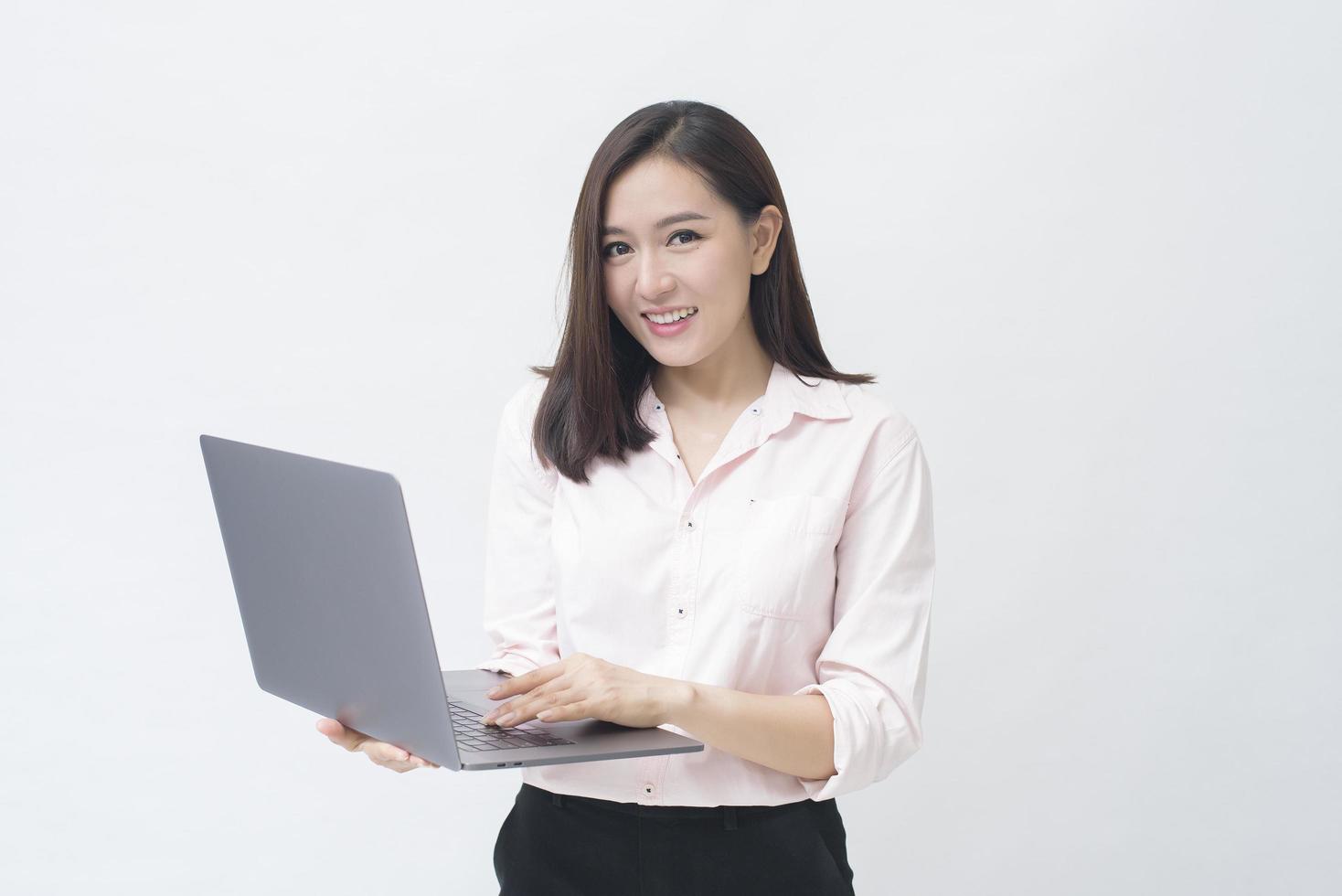 una mujer asiática sostiene una computadora portátil en un estudio blanco foto